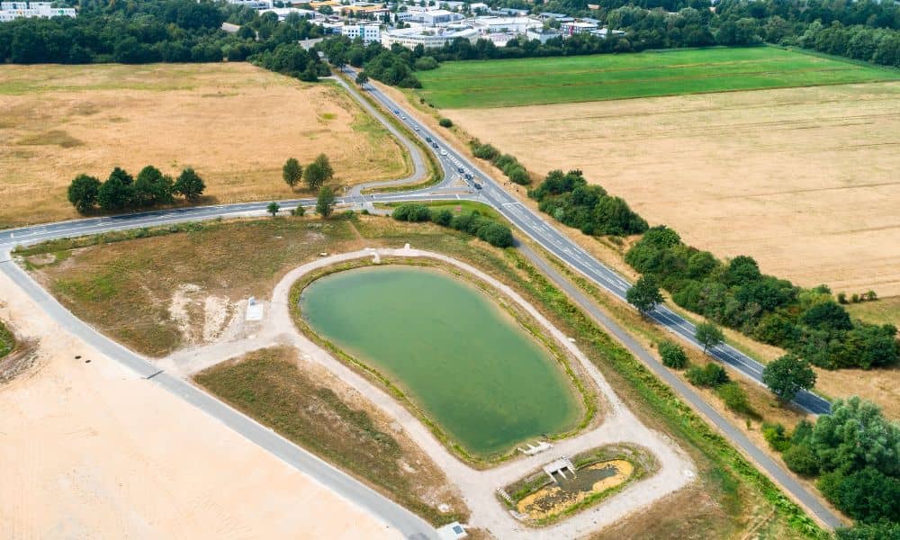Engineered stormwater detention basin with outlet structure near roadway development